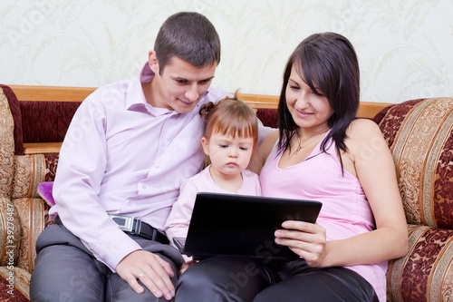 happy family with the child looks in the monitor of a laptop