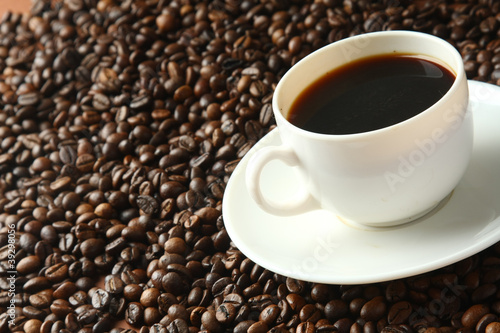 a cup of coffee on coffee beans, closeup