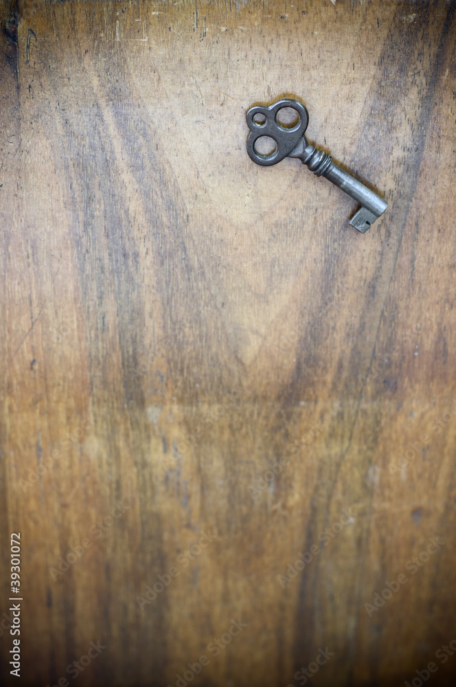 Old key on weathered walnut wood background Old key on weathered walnut wood background