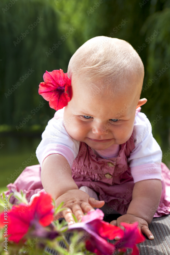baby girl reaching flowers