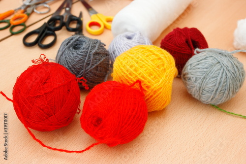 Colorful woolen yarns and scissors on the table