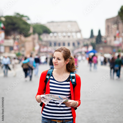 Pretty young female tourist holding a map
