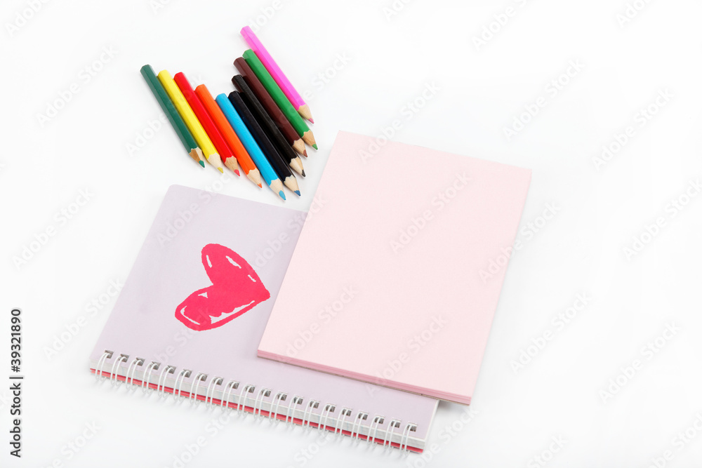 Notebook and colored pencils on a white background. Notebook and colored pencils on a white background.
