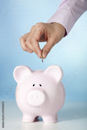 Female hand putting coin into a piggy bank