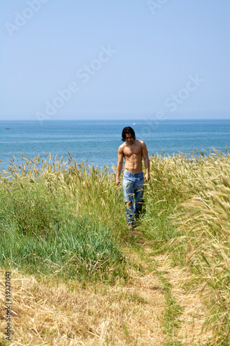 Muscular male model on the beach walking in a corn field © fmarsicano