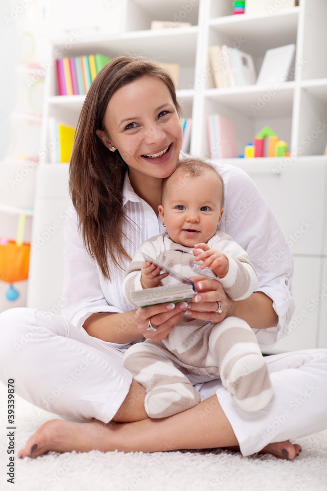 Baby girl reading her first book with mother