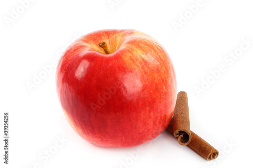 Red apple with cinnamon sticks on white background