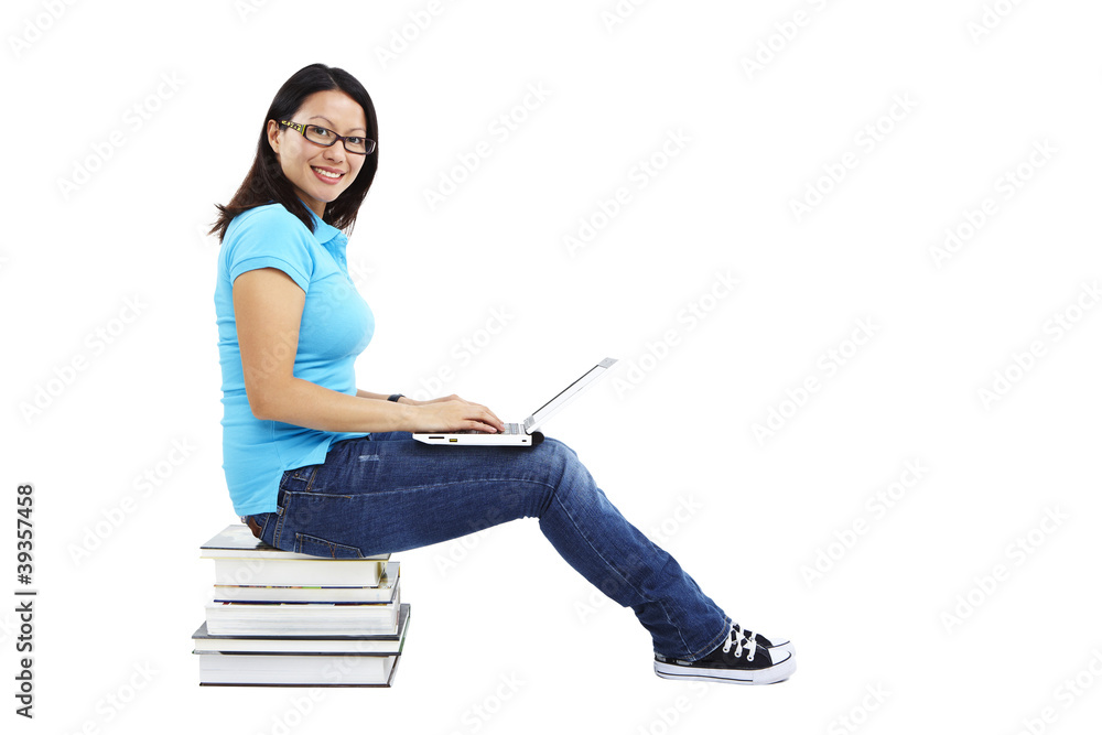 Studentin sitzt auf Bücherstapel mit Laptop Studentin sitzt auf Bücherstapel mit Laptop