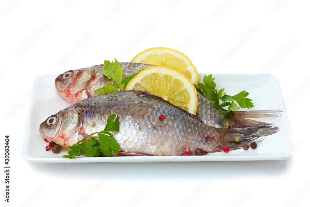 Fresh fishes with lemon and parsley on plate isolated on white