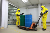 Two specialists in protective uniforms dealing with barrels
