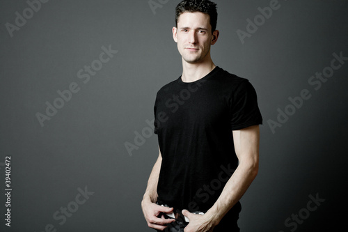 Young man in black t-shirt on gray background.