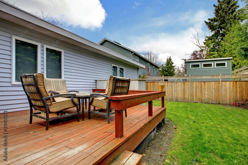 Grey small house with simple deck and outdoor chairs.