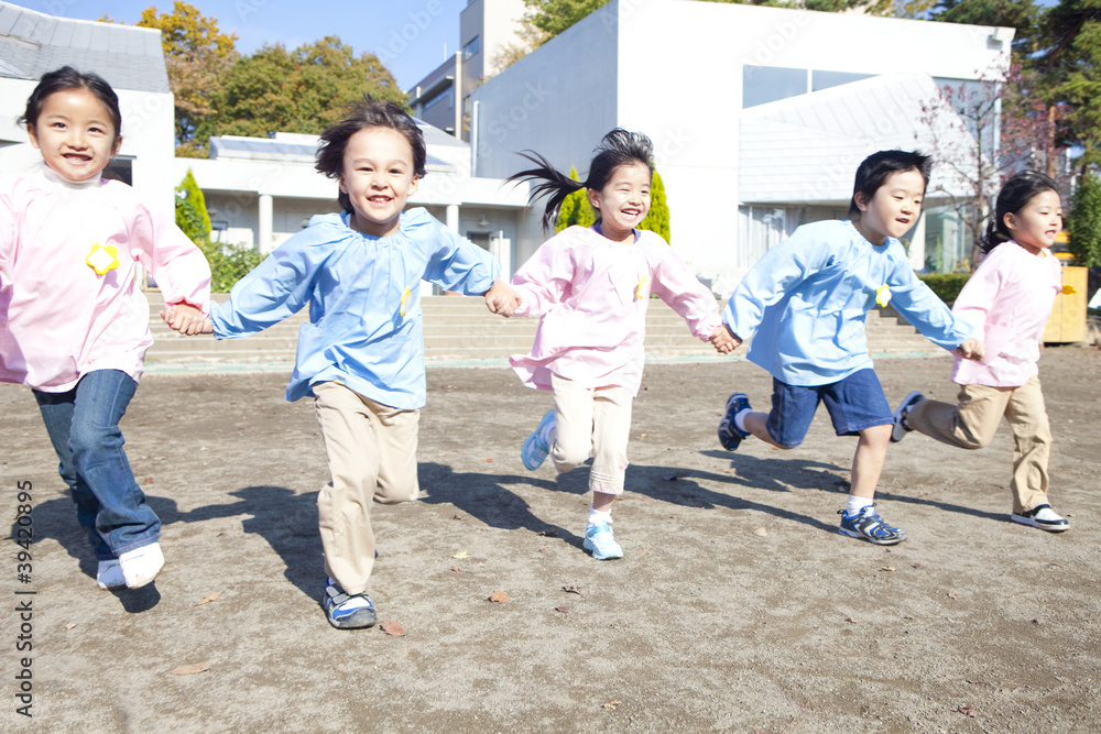 手を繋いで園庭を走る幼稚園児5人