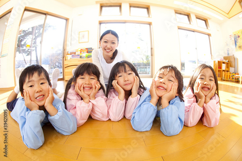 頬杖をついて微笑む幼稚園児と笑顔の幼稚園教諭