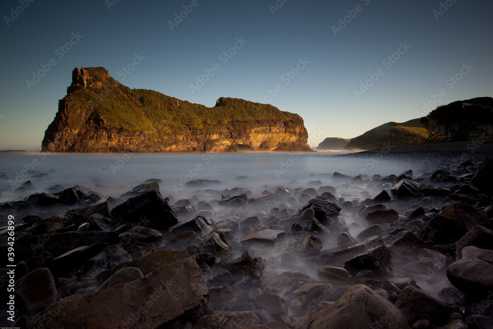 long exposure image of island and black rocks with blurred ocean