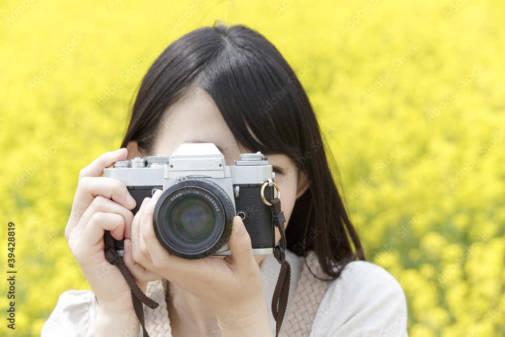 菜の花畑でカメラを構える笑顔の女性 菜の花畑でカメラを構える笑顔の女性