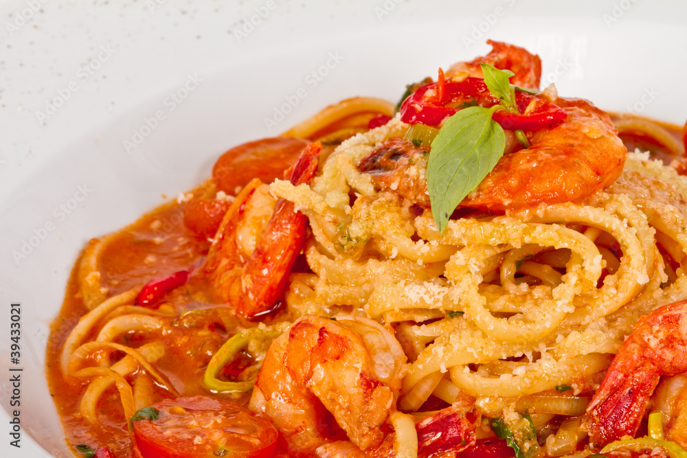 A plate of linguini with sauteed shrimp, tomato, chili and oliv A plate of linguini with sauteed shrimp, tomato, chili and oliv