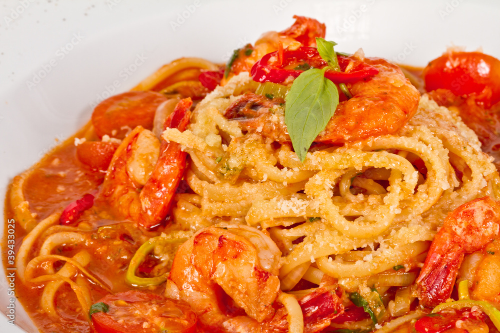 A plate of linguini with sauteed shrimp, tomato, chili and oliv A plate of linguini with sauteed shrimp, tomato, chili and oliv