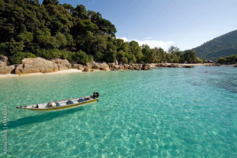 Boat in crystal clear waters at a paradise island in Malaysia