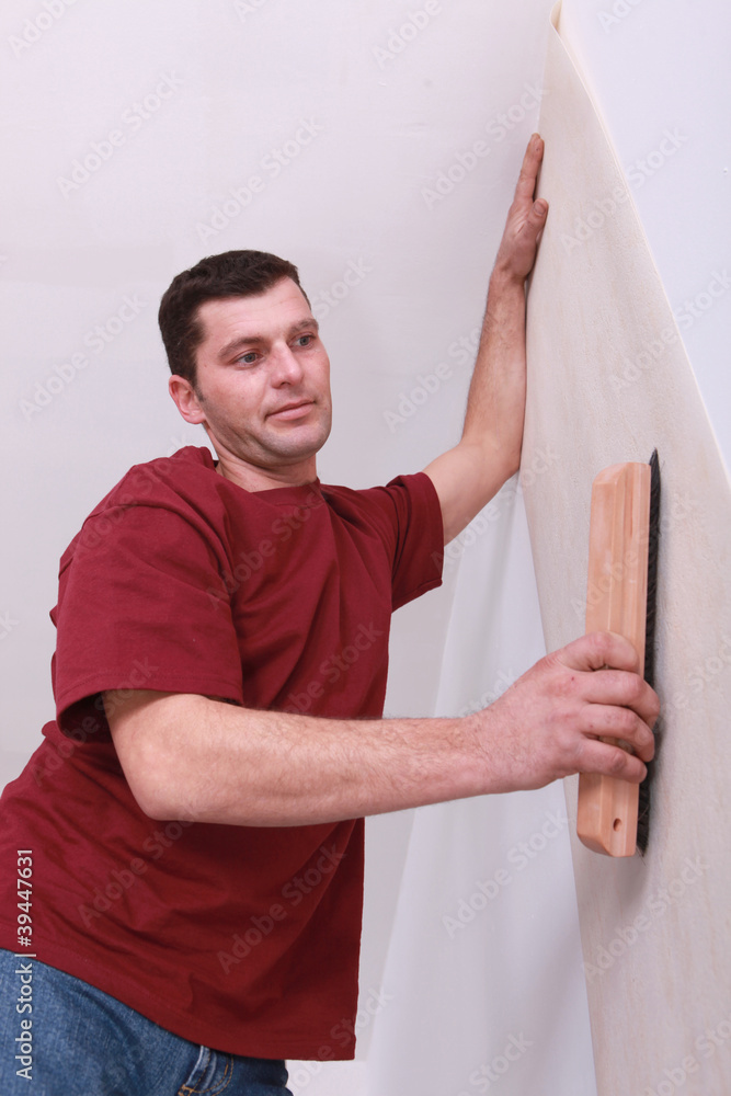 Decorator smoothing down wallpaper with a brush Decorator smoothing down wallpaper with a brush