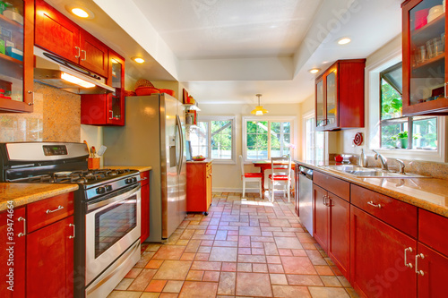 Charming cherry wood kitchen with tile floor.