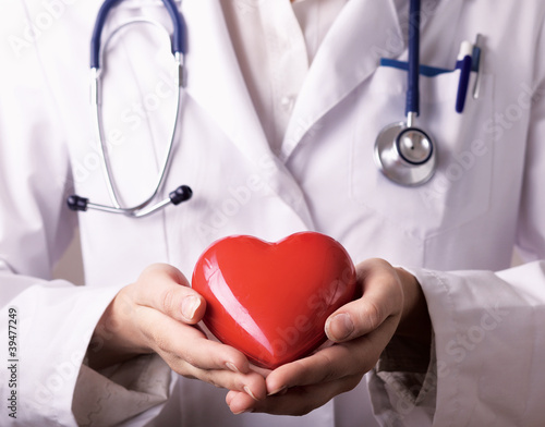 Female doctor with stethoscope holding heart