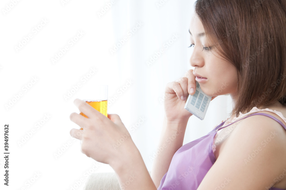 アイスティーを飲みながら携帯電話で通話する女性