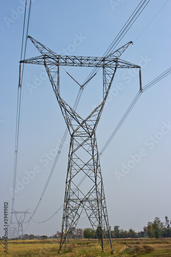 electricity pylon in field and blue sky