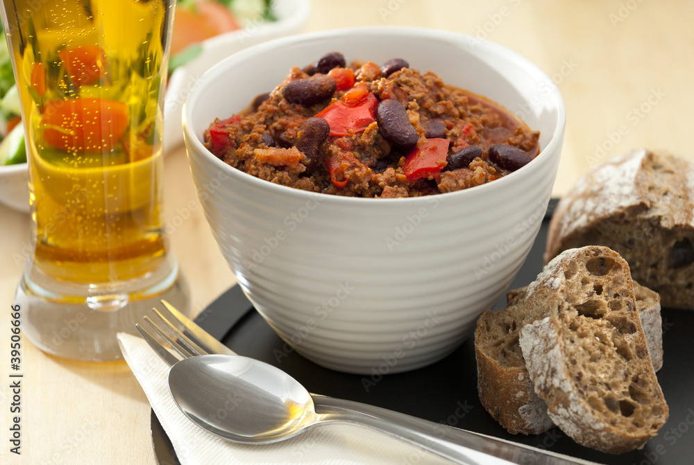 Hot and spicy minced meat chili with fresh bread and cold beer Hot and spicy minced meat chili with fresh bread and cold beer