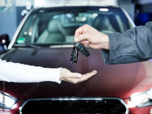 фотографія Key delivery between customer and mechanic in front of new car