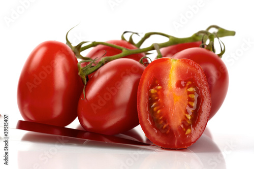 Frische Roma Tomaten mit Messer vor weißem Hintergrund