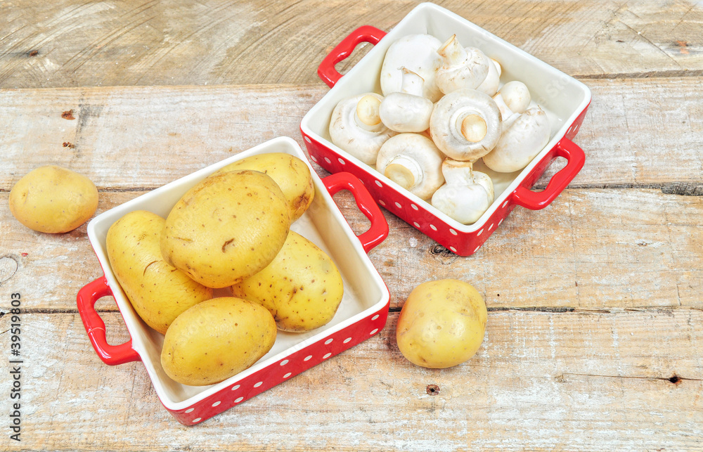 Raw mushrooms and potatoes in red trays