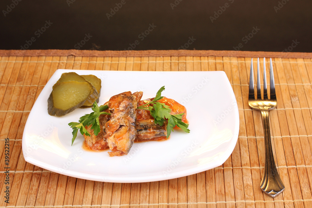Tasty sardines on plate on wooden mat on brown background