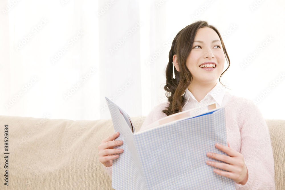 ソファに座りながら雑誌を読む女性 ソファに座りながら雑誌を読む女性
