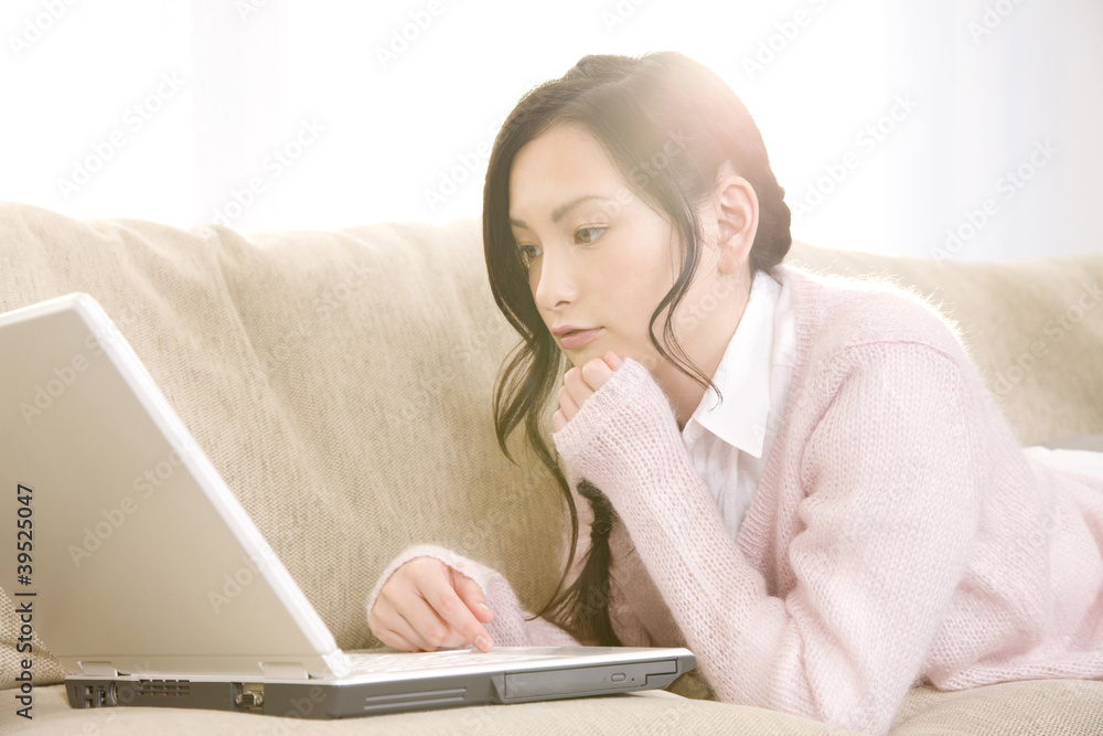 ソファの上でうつ伏せになりノートパソコンを使っている女性 Stock Photo Adobe Stock