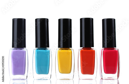 Five colorful nail polish bottles in a row with black caps, beauty and manicure products, isolated on white background