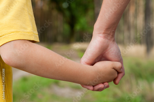 Mother holding a hand of his son outdoors