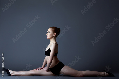 Beauty girl in black gymnast costume sit on split