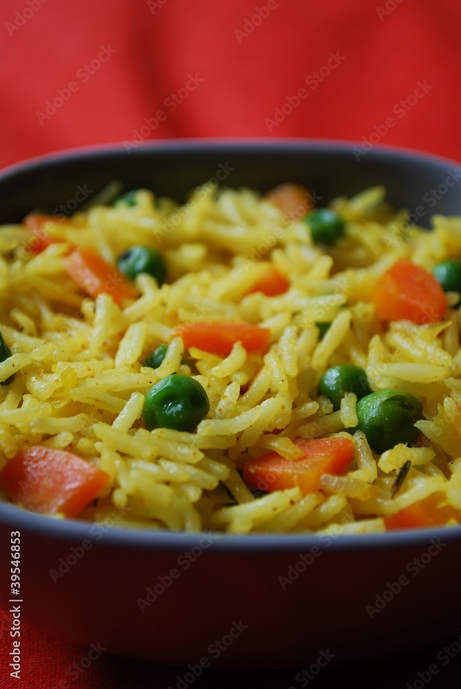 A bowl of yellow basmati rice with carrots, peas and curry A bowl of yellow basmati rice with carrots, peas and curry