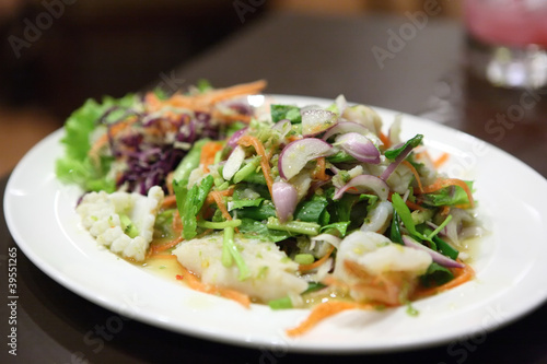 Thai dressed spicy salad with prawn and fish in wood background