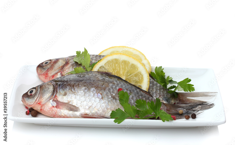 Fresh fishes with lemon and parsley on plate isolated on white Fresh fishes with lemon and parsley on plate isolated on white