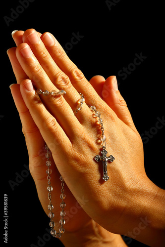 Christian human praying with rosary in hands