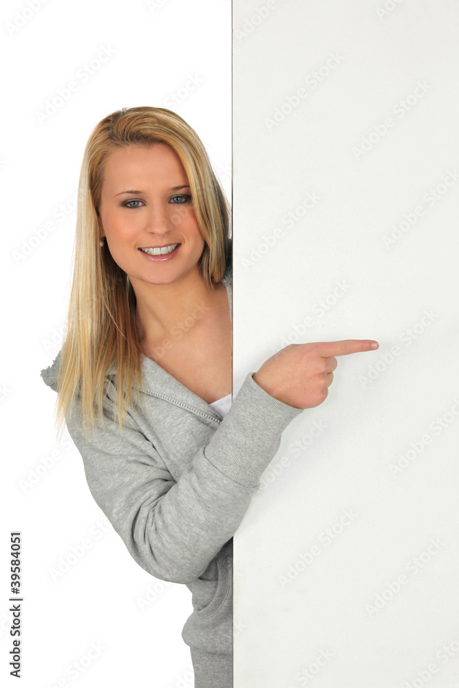 Young woman pointing at a board left blank for your message Young woman pointing at a board left blank for your message