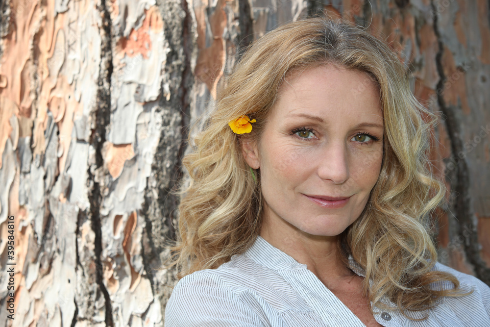 Blond woman sat in front of tree Blond woman sat in front of tree
