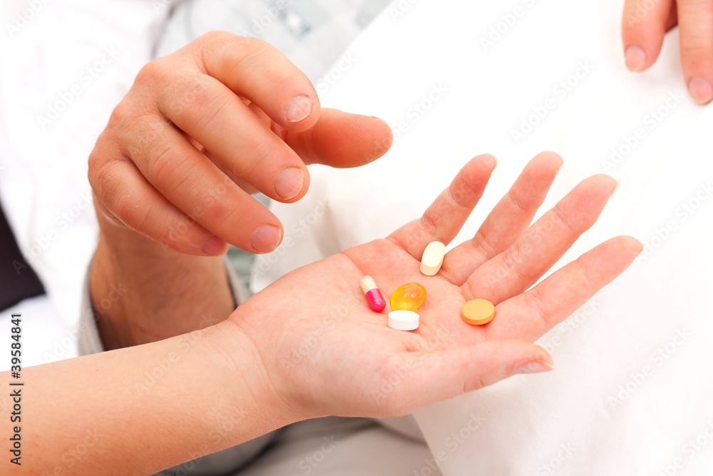 A nurse 's hands givng pills and drugs to a laying senior man. A nurse 's hands givng pills and drugs to a laying senior man.