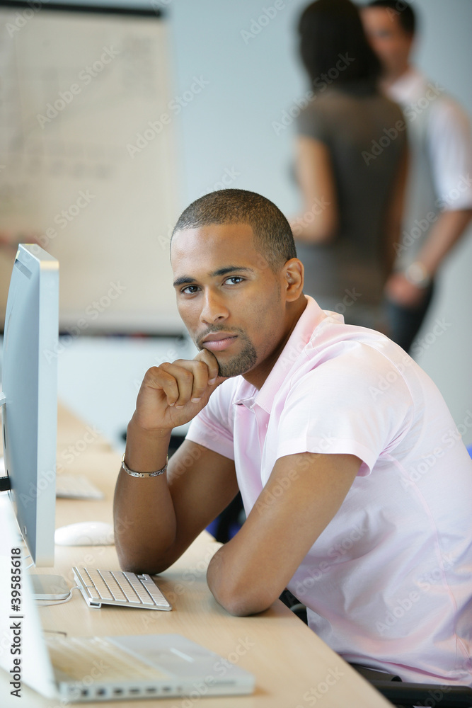 Naklejka premium Casual worker thinking whilst sat at computer