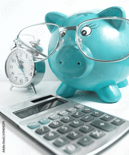 Business concept-piggy bank with glasses,calculator and a clock