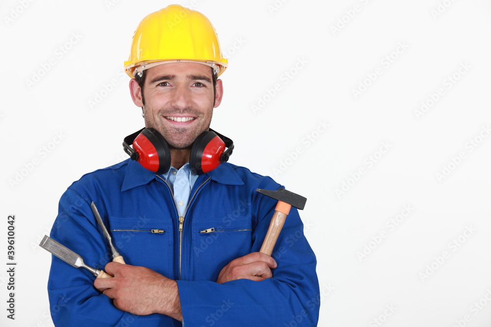 craftsman with safety helmet and earmuffs holding tools craftsman with safety helmet and earmuffs holding tools