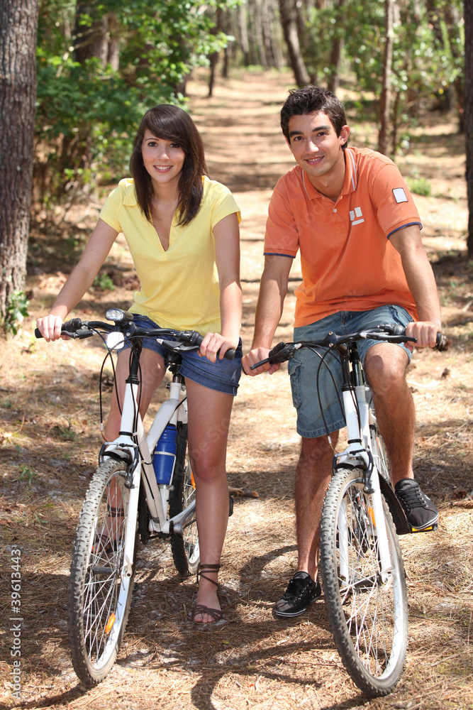 Young couple riding bikes in a forest Young couple riding bikes in a forest
