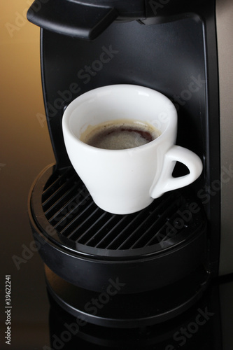Espresso machine and cup of coffee on brown background